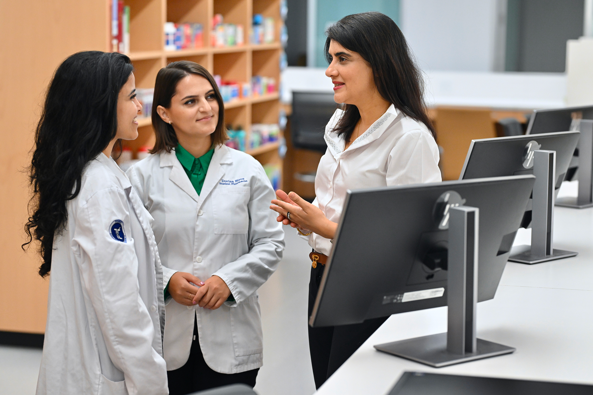 Two students talking with a faculty member in classroom