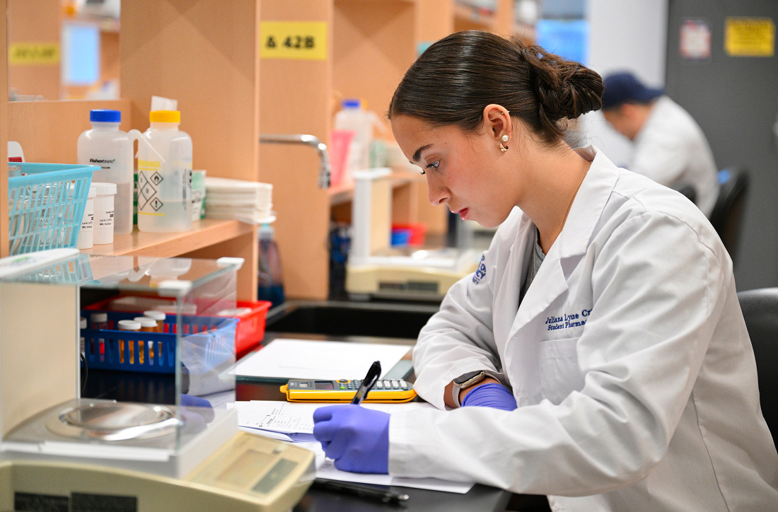 Student pharmacist doing math in facility.