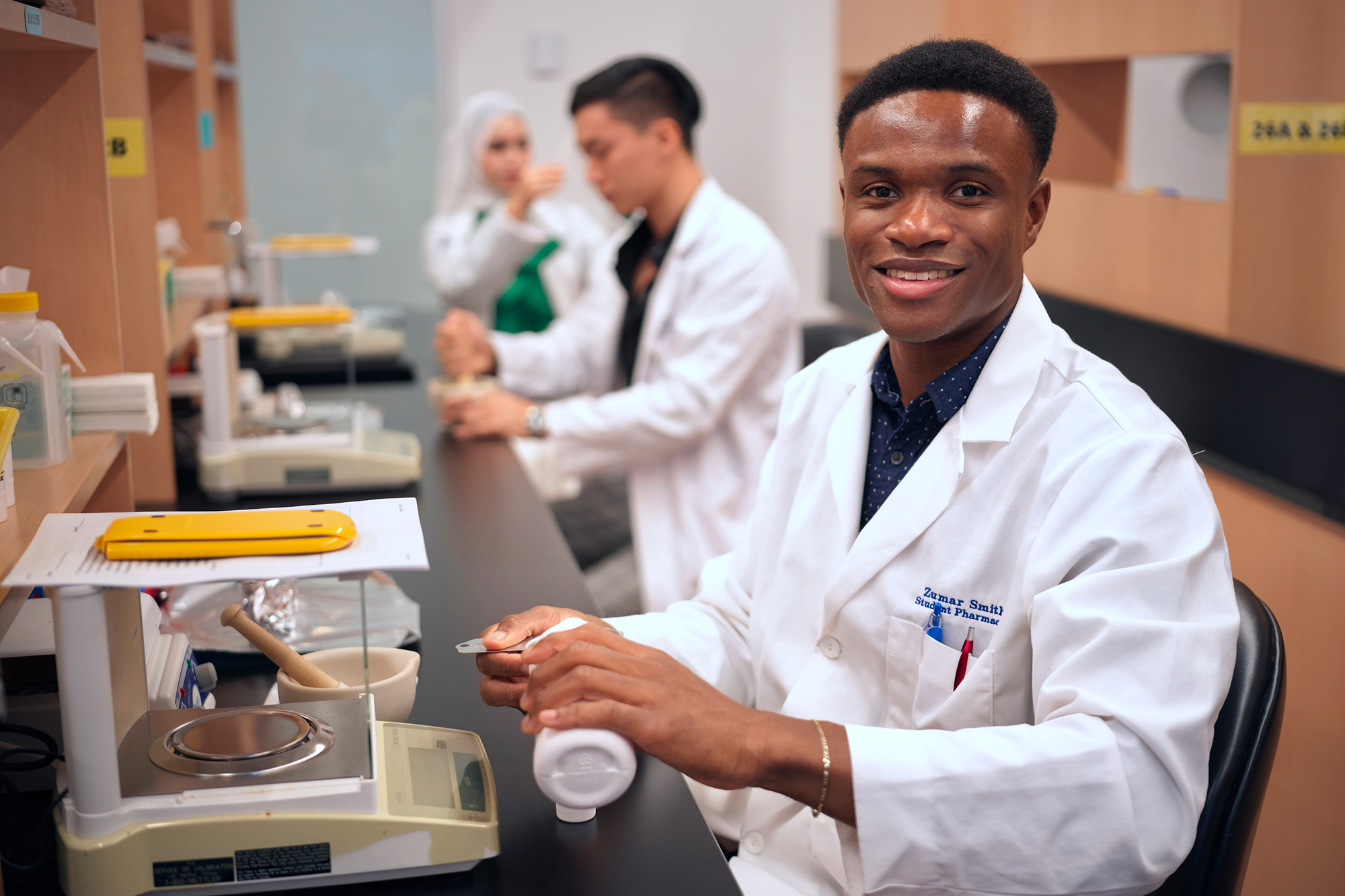 Male student smiling while working with medicine in classroom