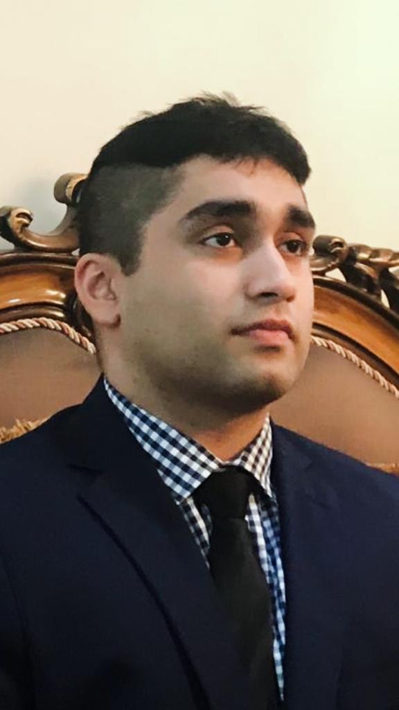 Headshot of Ahmad Naeem, PharmD in suit and tie, looking away from the camera
