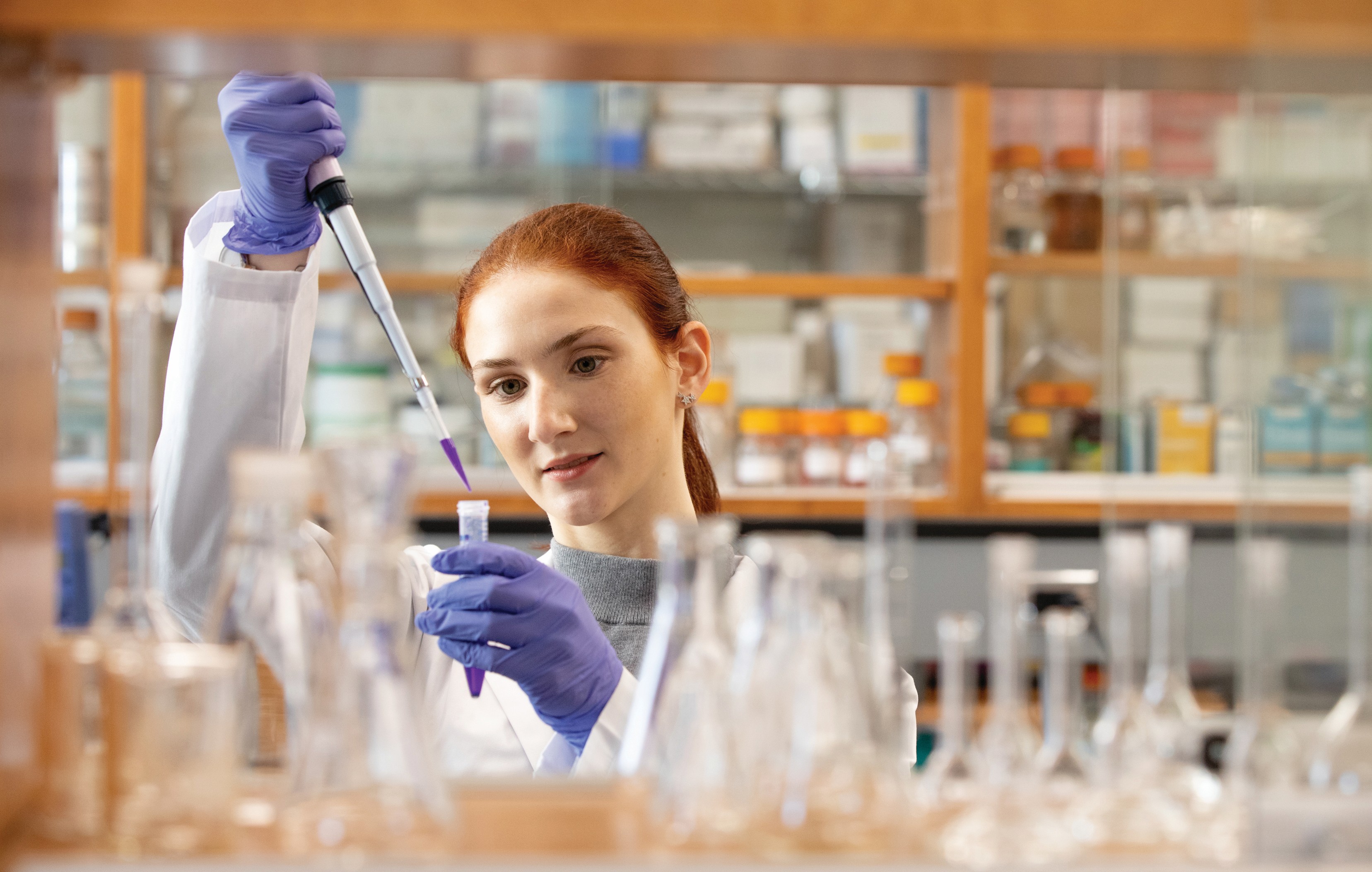 student in lab holding up glassware and examining contents