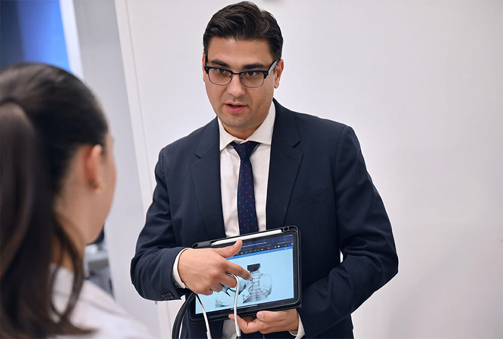 Pharmacy Assistant Professor Roman Fazylov pointing to an image on a tablet to show to female TCOP student